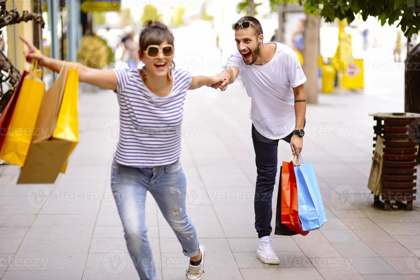 ritratto di allegro caucasico giovane coppia uomo e donna Tenere molti carta borse dopo shopping mentre a piedi e parlando su strada. contento famiglia coppia con pacchi all'aperto. acquisto concetto foto