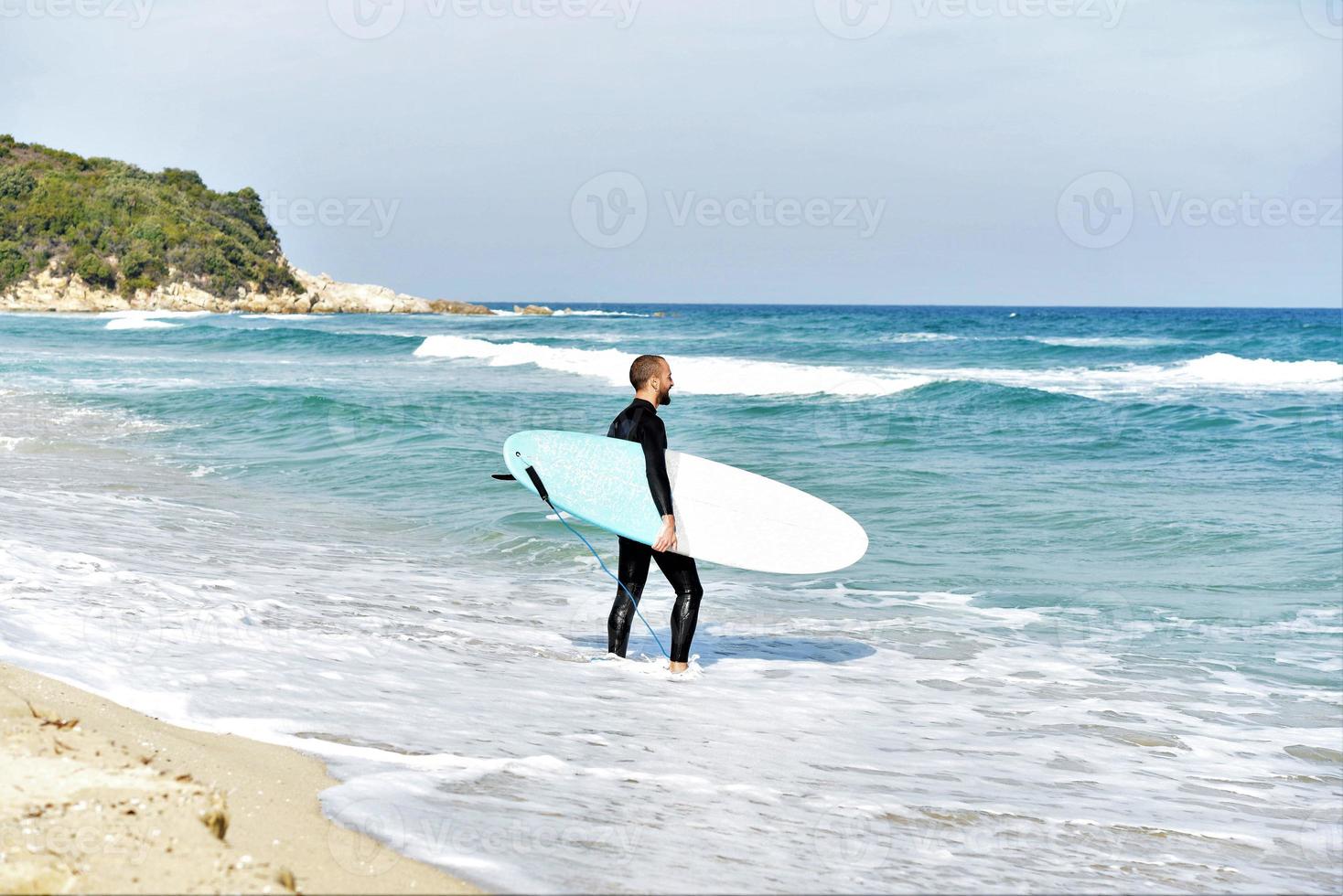 un' uomo è in piedi con un' Surf nel il suo mani su il mare costa. foto