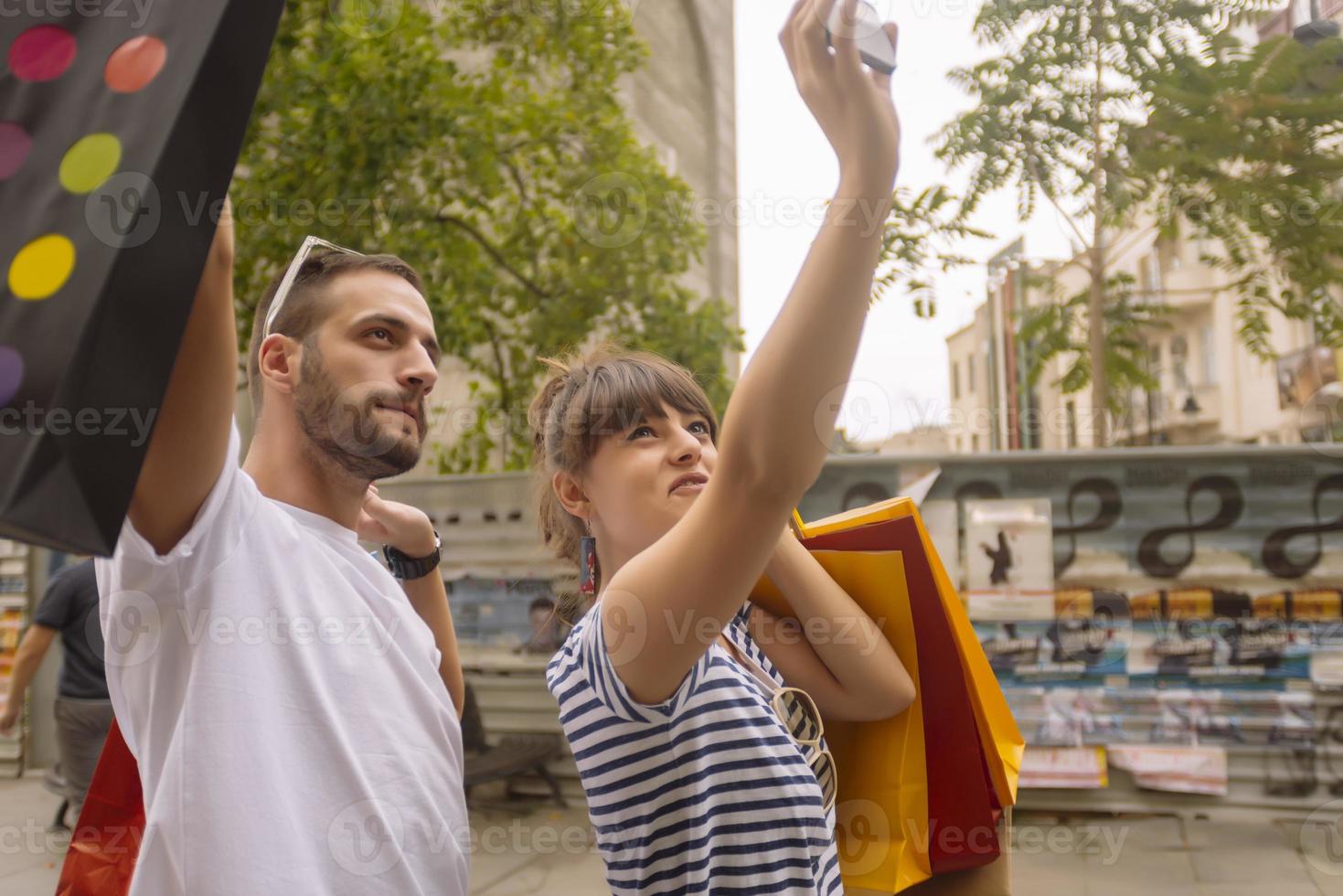 ritratto di allegro caucasico giovane coppia uomo e donna Tenere molti carta borse dopo shopping mentre a piedi e parlando su strada. contento famiglia coppia con pacchi all'aperto. acquisto concetto foto