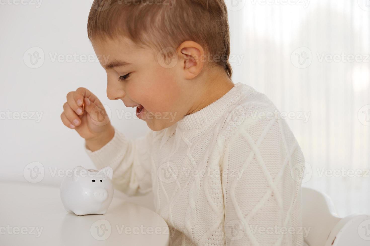 poco ragazzo mettendo i soldi moneta in porcellino banca per Salvataggio i soldi. ricchezza, bilancio, investimento, finanza concetto. bambino e i soldi scatola, salvadanaio. foto