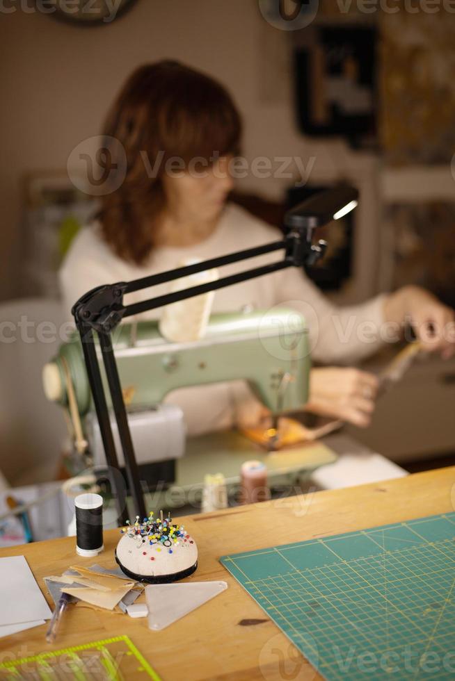 donna cucire tessuto con un' Vintage ▾, retrò cucire macchina. moda, creazione e sartoria. processi di cucire nel Atelier o officina. speciale passatempo. foto