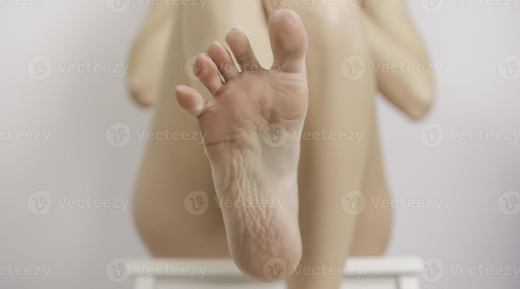 un' giovane donna si applica lozione per sua piedi foto
