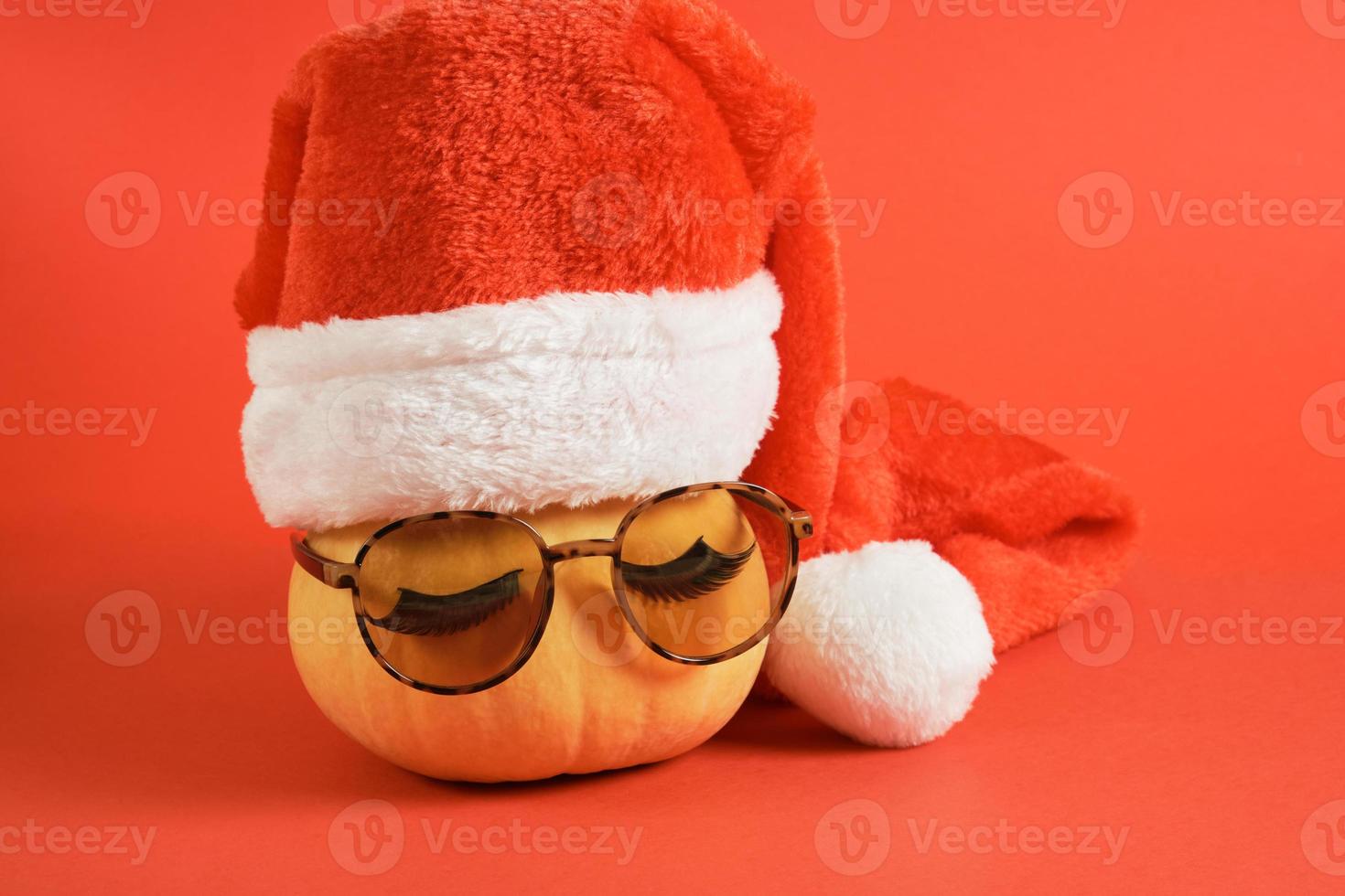 zucca con occhiali da sole e rosso Santa Claus cappello su un' rosso sfondo, Natale vacanze nel caldo paesi concetto foto