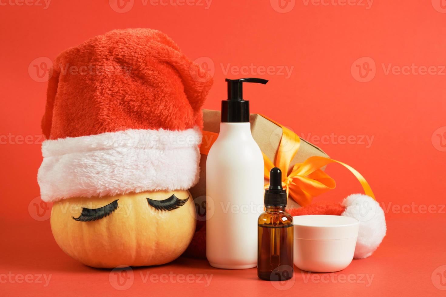 finto su cosmetico bottiglie, avvolto Natale regalo e zucca nel Santa cappello e falso ciglia foto