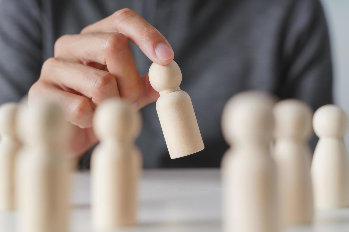 uomo mano sceglie di legno piolo Bambola. comando e attività commerciale squadra creativo pensiero e umano risorse per lavoro di squadra o squadra giocatore concetto. foto