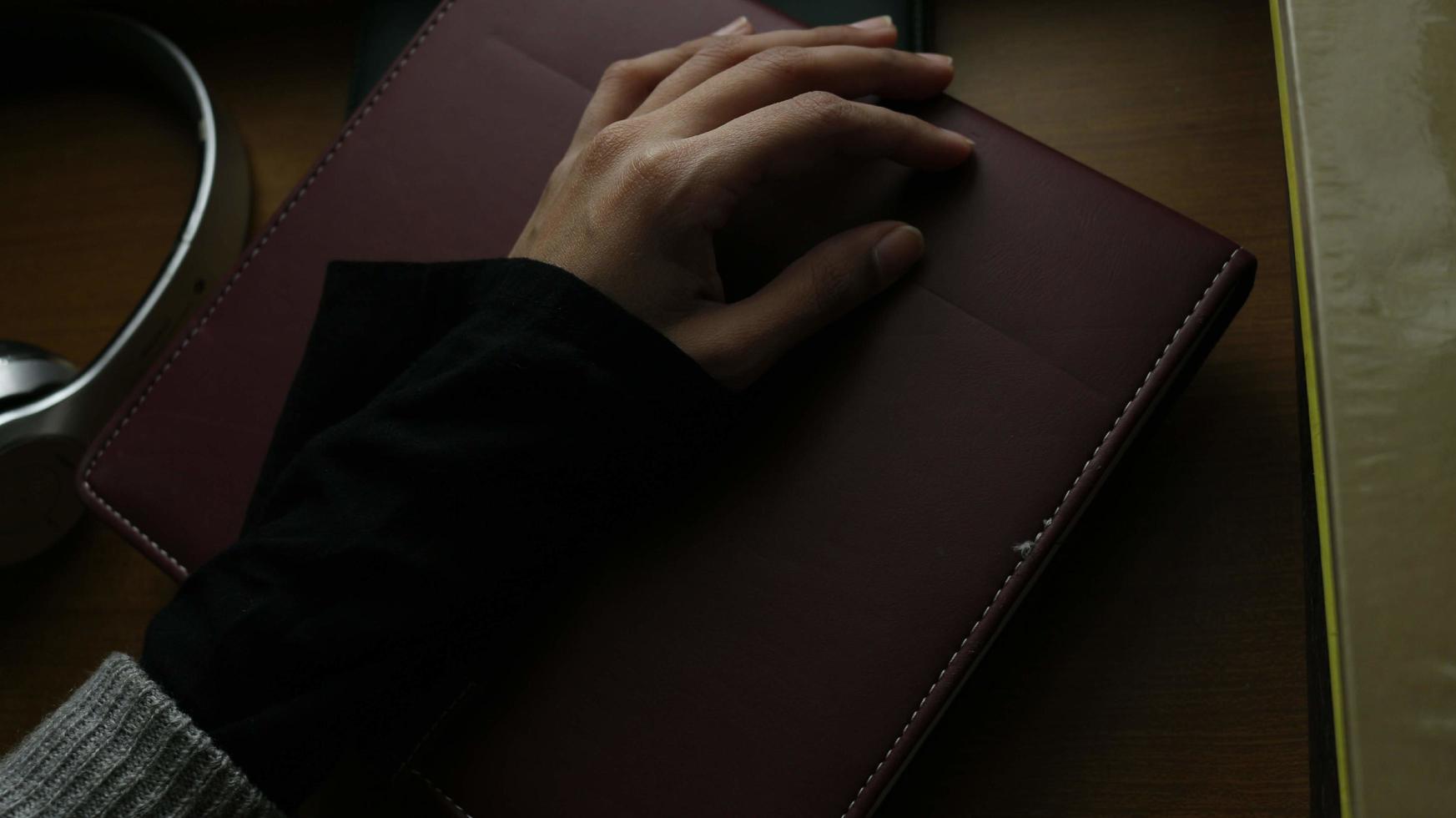 avvicinamento di un' donna di mano su un' libro nel un' cupo ambientazione foto
