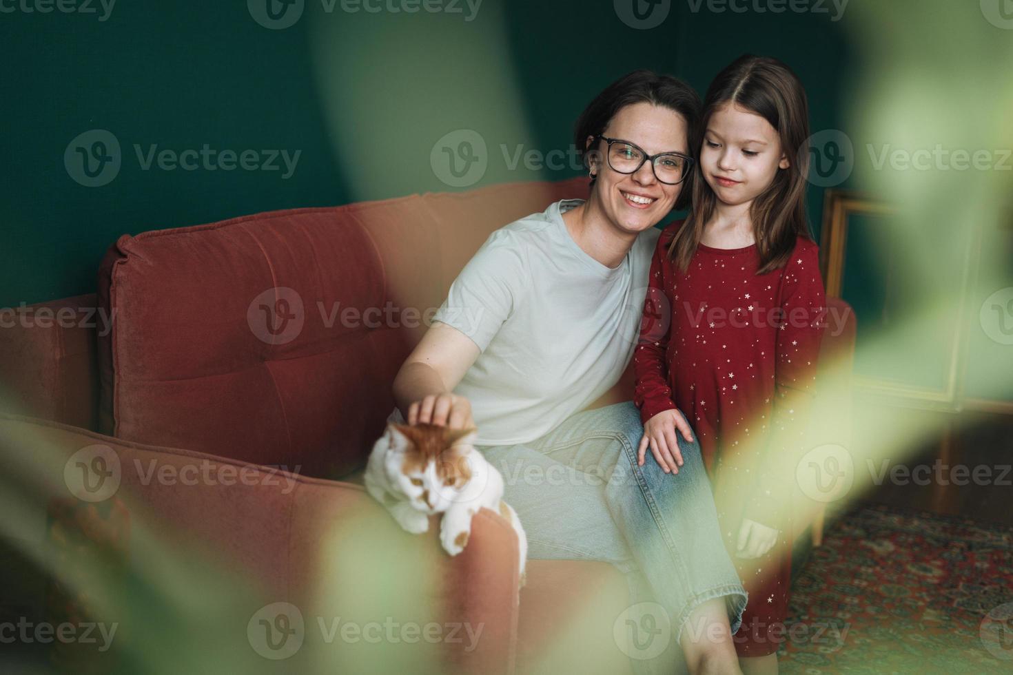 contento famiglia mamma e figlia insieme con gatto su divano nel vivente camera a il casa foto