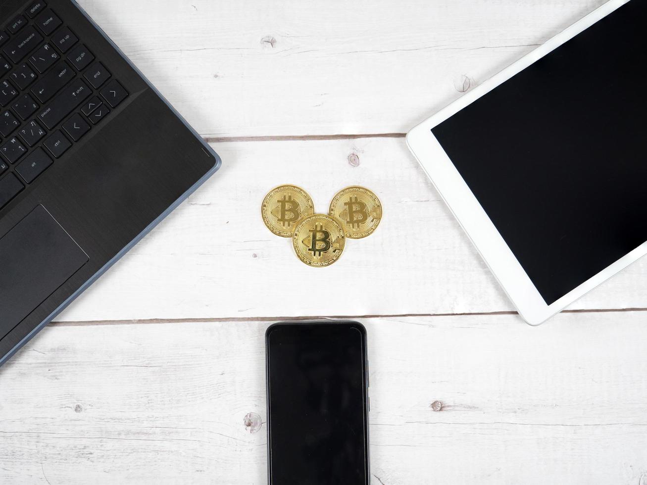 d'oro bitcoin su il scrivania con il computer portatile tavoletta e smartphone in giro superiore Visualizza il digitale i soldi crypto concetto foto