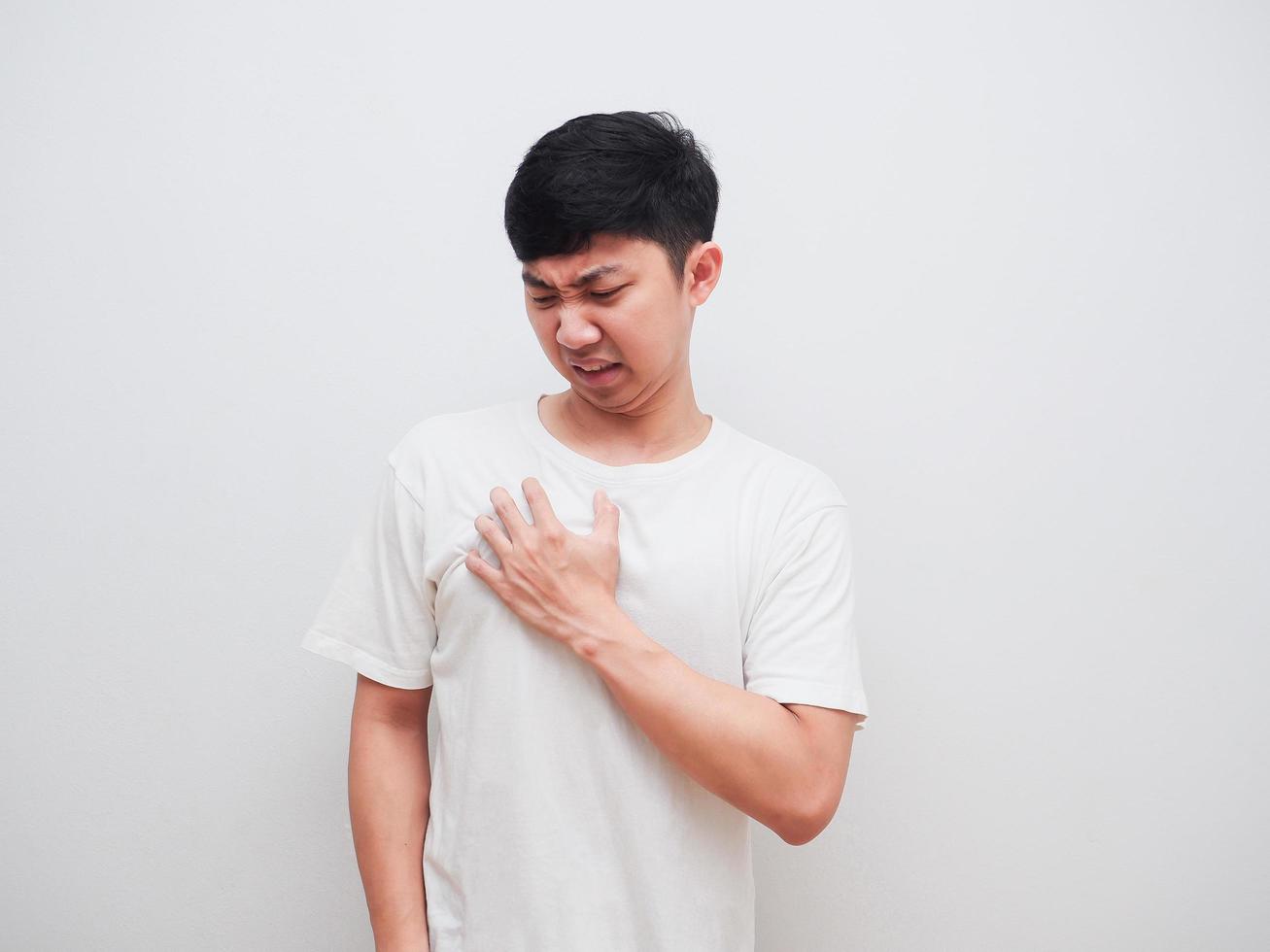 asiatico uomo toccare a il suo il petto infelice viso su bianca sfondo dolore concetto foto