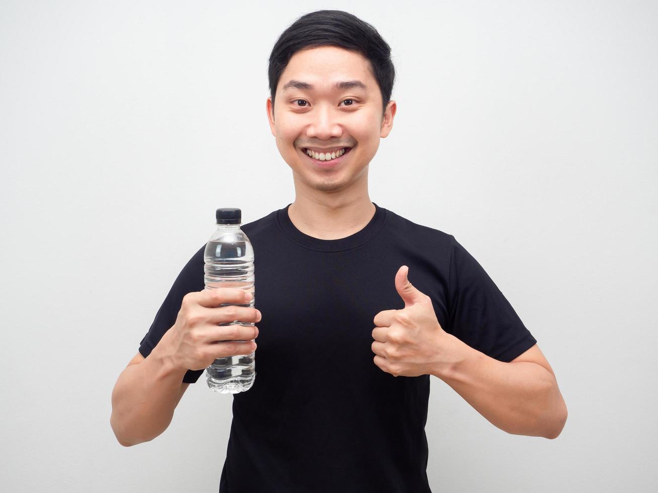 asiatico uomo Tenere acqua bottiglia e pollice su contento sorriso, allegro uomo con acqua bottiglia foto