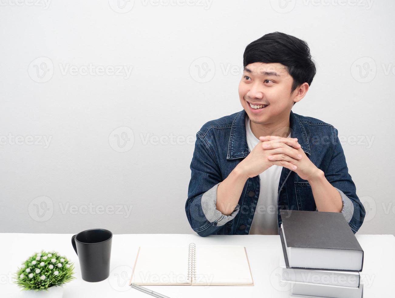 uomo sorridente jeans camicia sedersi a il scrivania posto di lavoro guardare a copia spazio foto