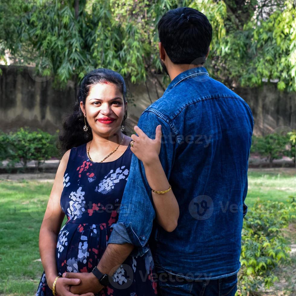 coppia indiana in posa per le riprese del bambino di maternità. la coppia è in posa in un prato con erba verde e la donna sta sbandierando il suo pancione nel giardino di lodhi a nuova delhi, india foto