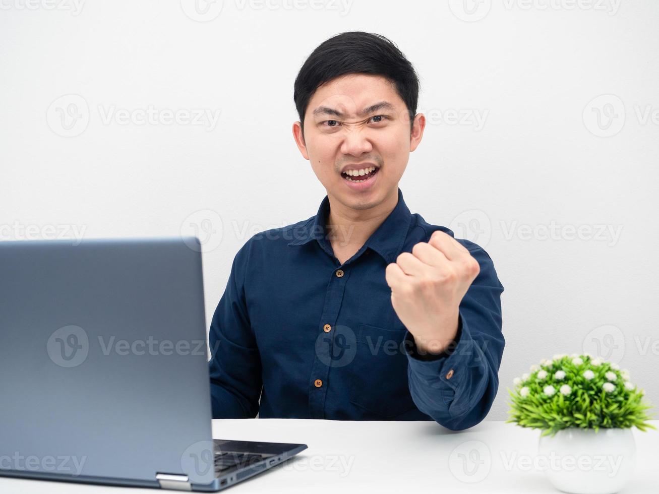asiatico uomo guardare a il computer portatile su il tavolo e mostrare cazzotto su sensazione contento di il suo opera foto