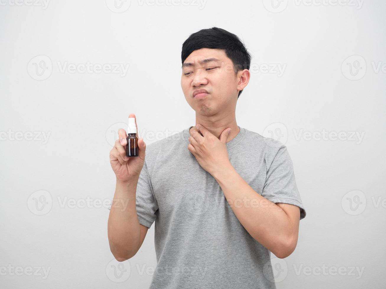 asiatico uomo sensazione dolorante gola e guardare a gola spray nel mano foto