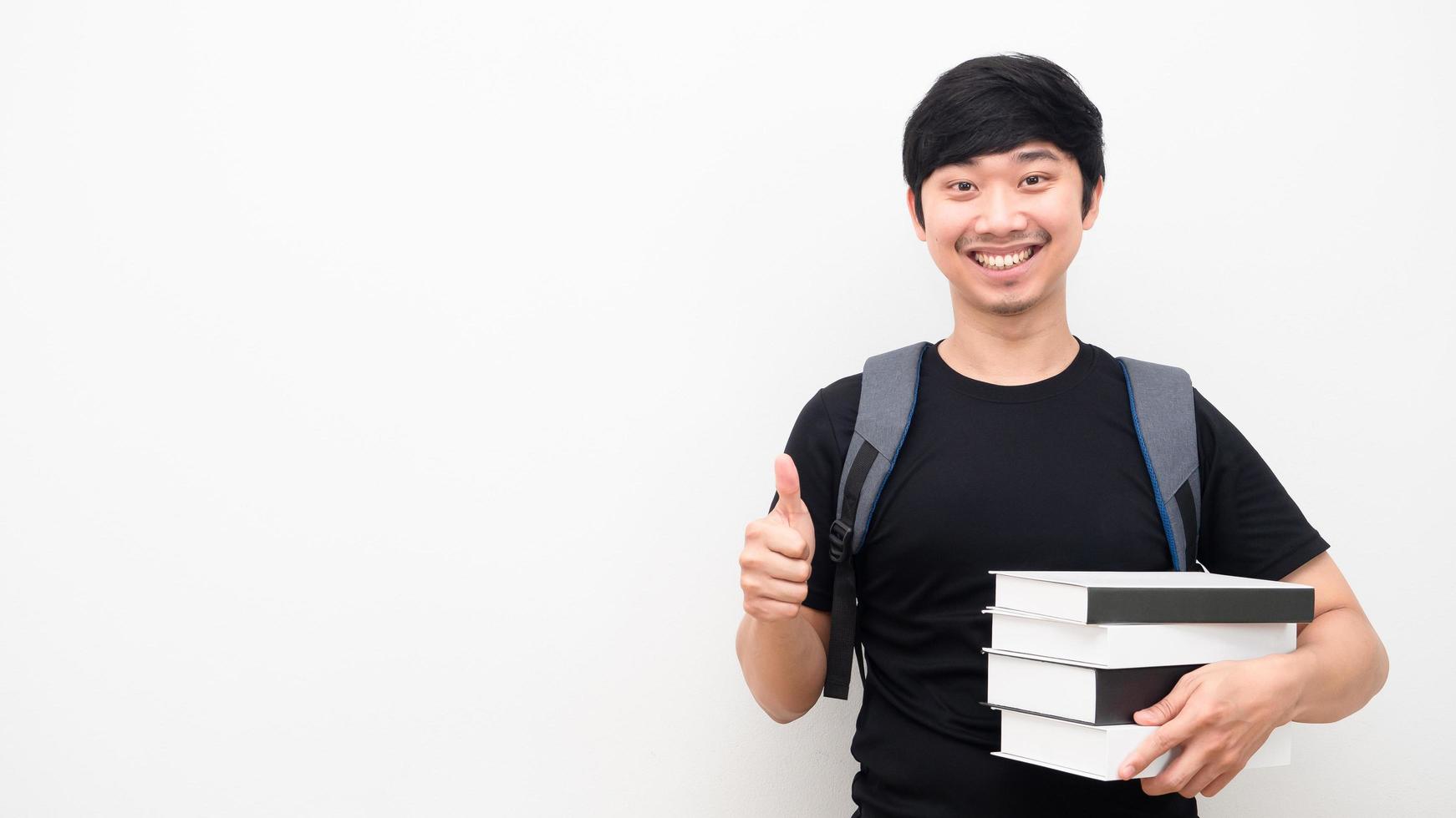 asiatico uomo con scuola zaino e Tenere libri pollice su contento Sorridi viso bianca sfondo copia spazio foto