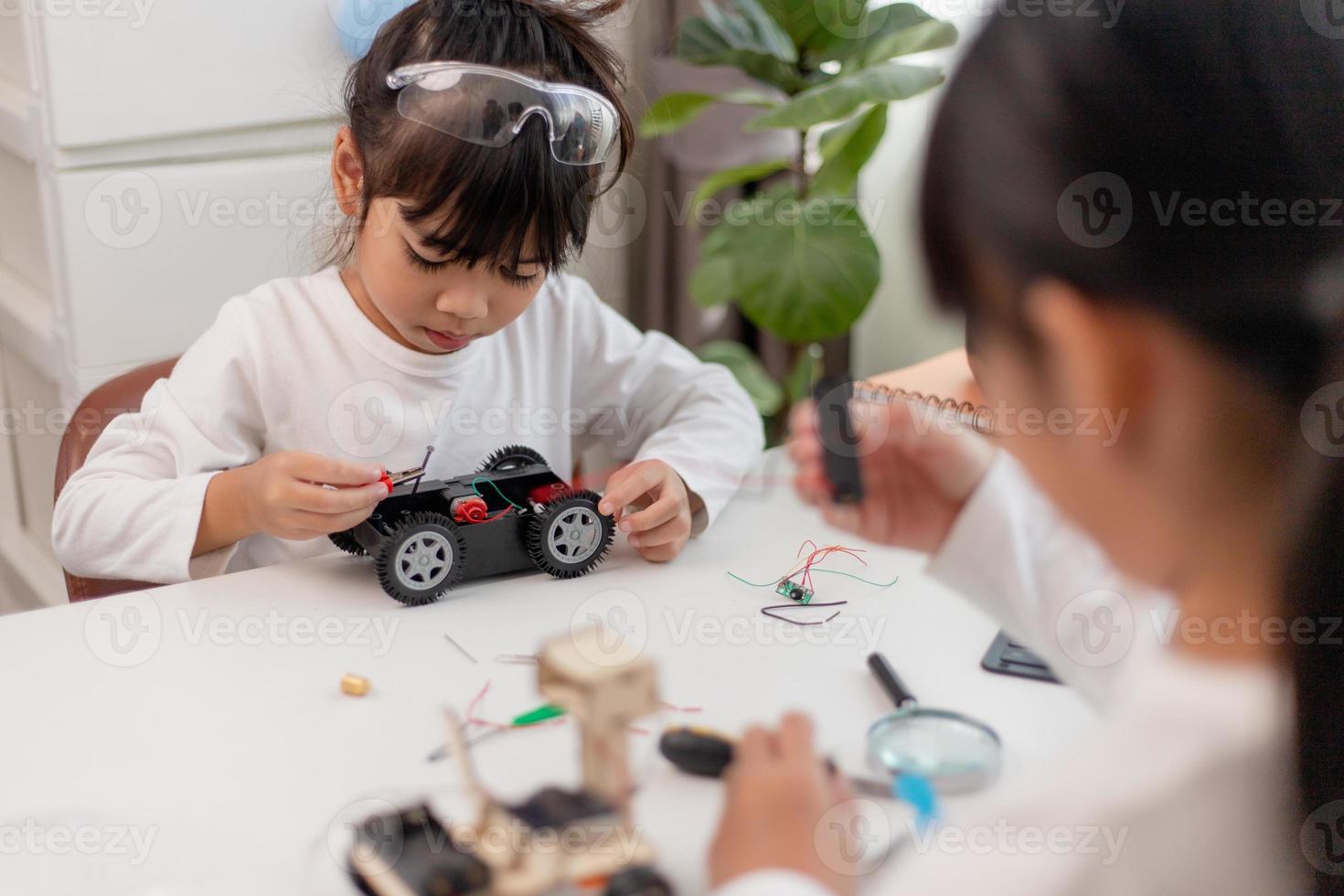 gli studenti asiatici imparano a casa a codificare auto robot e cavi di schede elettroniche in stelo, vapore, matematica ingegneria scienza tecnologia codice informatico in robotica per bambini concetto. foto