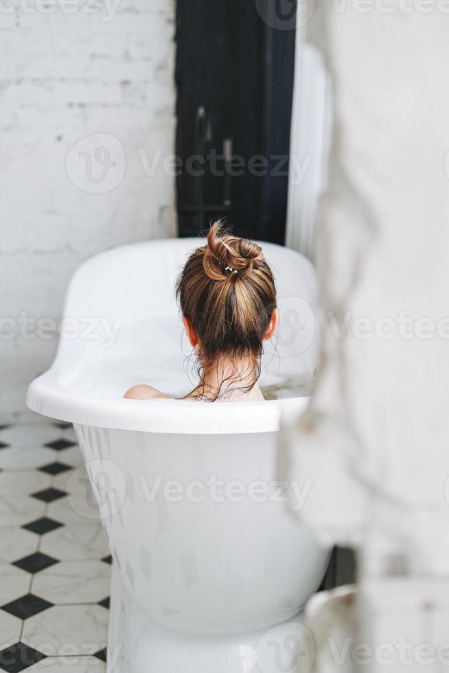 giovane contento donna assunzione bagno con schiuma a casa, trattare te stesso foto