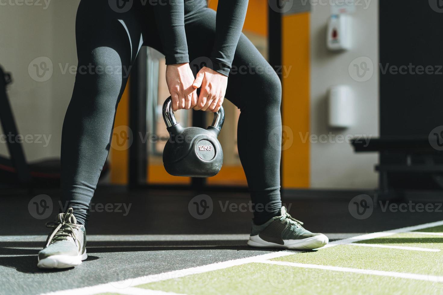 Ritaglia foto di giovane donna formazione sua muscoli con kettlebell nel fitness club