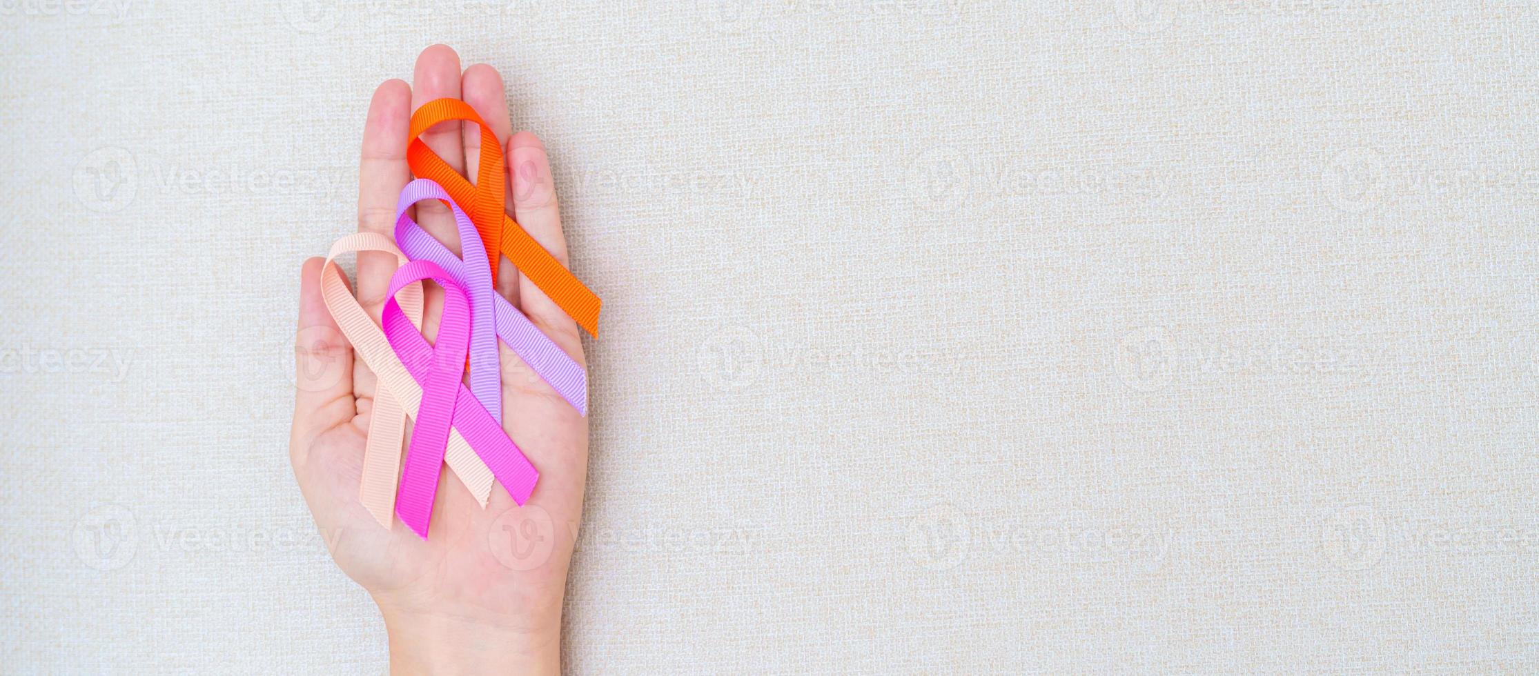 mondo cancro giorno, febbraio 4. mano Tenere arancia, rosa, pesca e viola nastri per supporto persone vivente e malattia. assistenza sanitaria e medico concetto foto