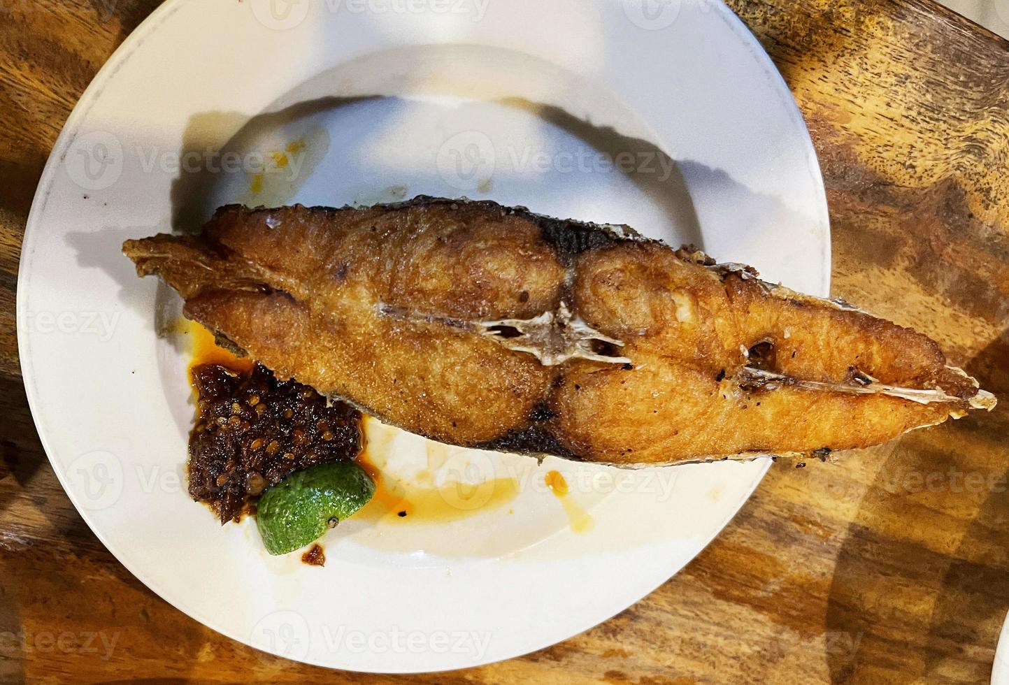 delizioso fritte spagnolo sgombro pesce con speziato salsa e agrume servito su bianca piatto foto