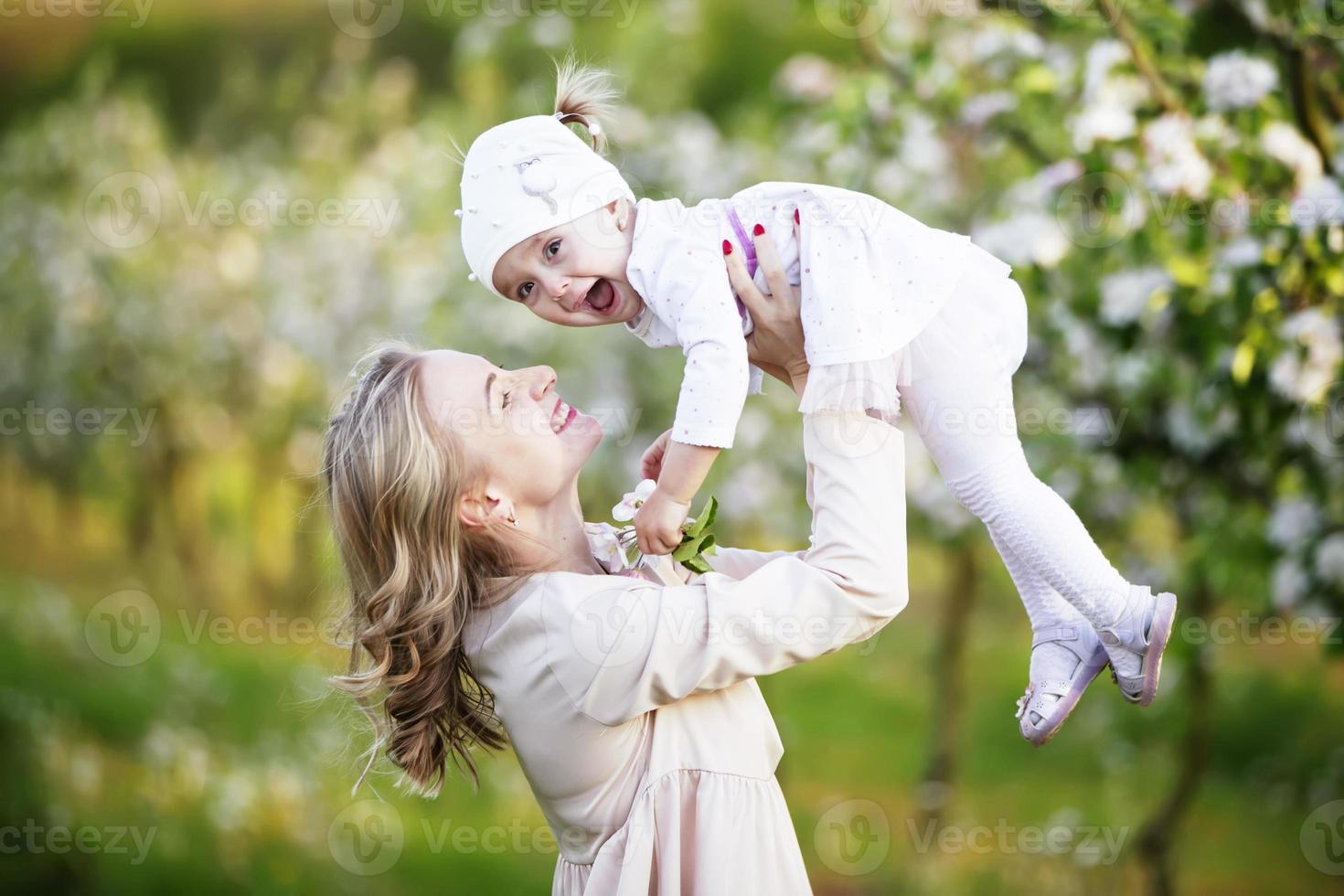 mamma con un' poco figlia nel un' fioritura giardino. contento maternità. contento madre e poco figlia ritratto all'aperto. La madre di giorno concetto foto