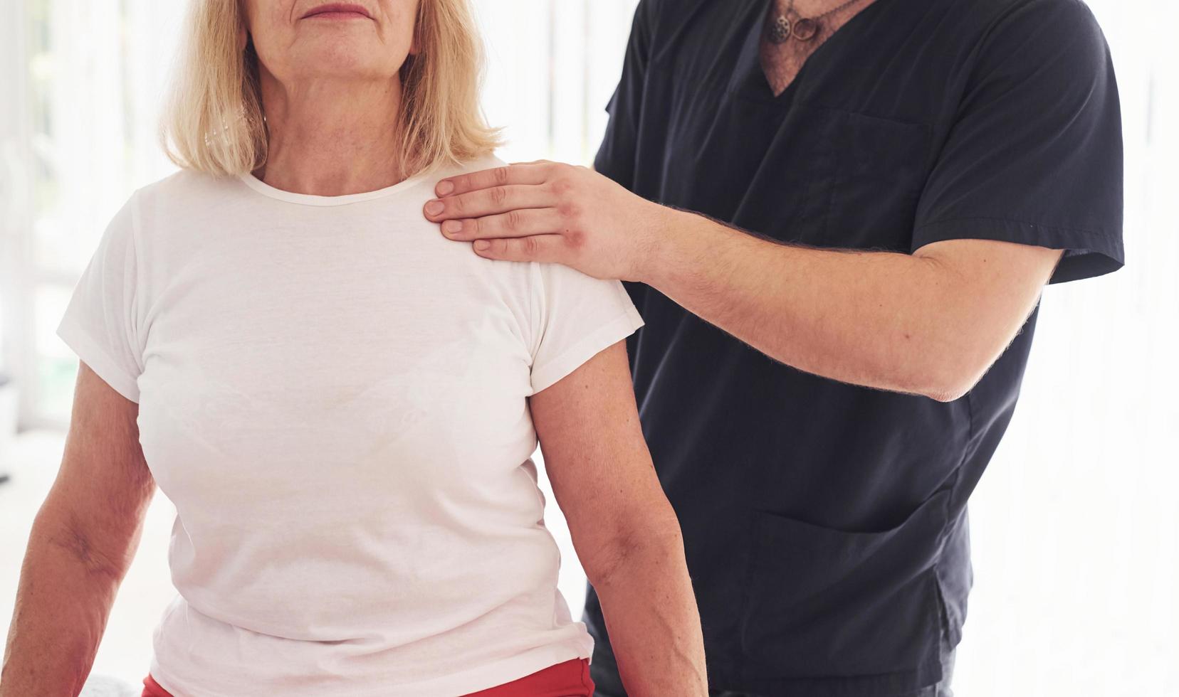 più vecchio donna avere un' visitare nel clinica e avendo riabilitazione. maschio istruttore porzione sua foto