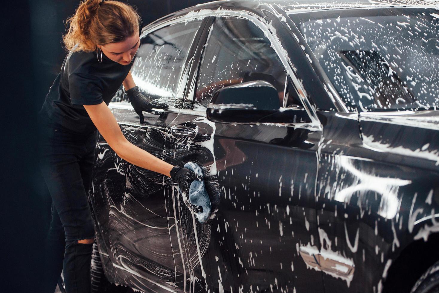 salviette veicolo quello è nel bianca sapone. moderno nero automobile ottenere puliti di donna dentro di auto lavare stazione foto