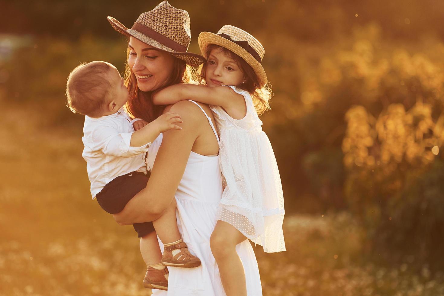 contento famiglia di madre, poco figlio e figlia la spesa gratuito tempo su il campo a soleggiato giorno tempo di estate foto