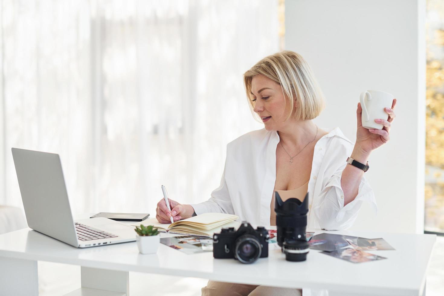 di mezza età donna nel elegante Abiti è a casa. fotografo con telecamera foto