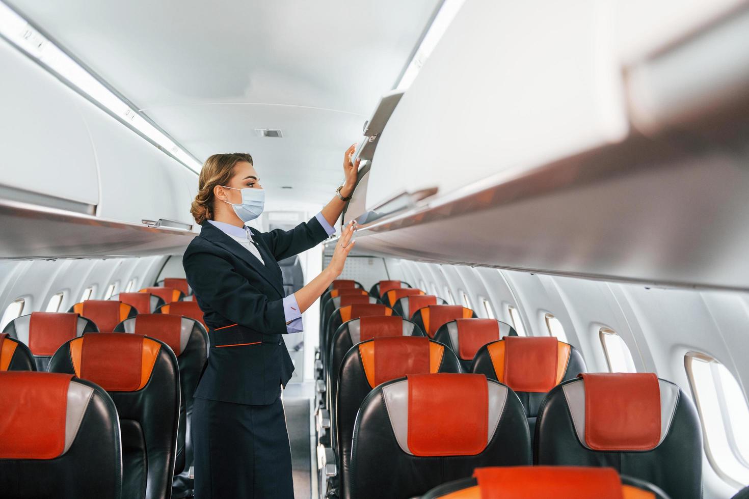 nel maschera. giovane hostess su il opera nel il passanger aereo foto