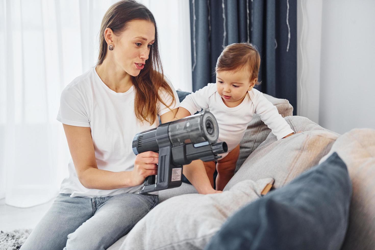 poco parte di il vuoto più pulito. madre con sua poco figlia è in casa a casa insieme foto