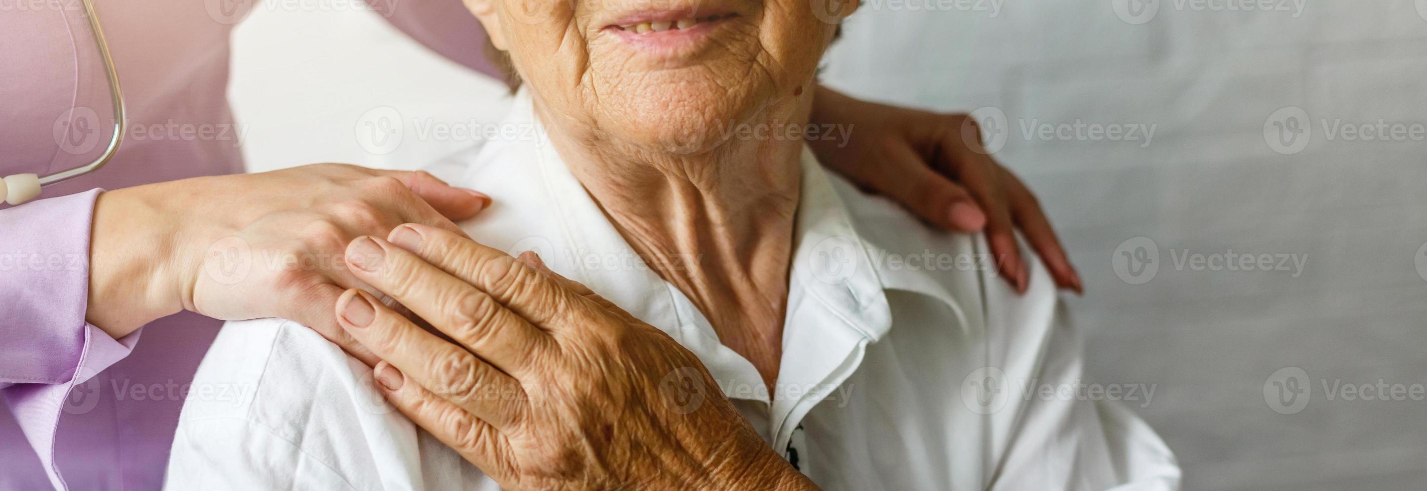 anziano femmina mano Tenere mano di giovane badante a assistenza infermieristica domiciliare.geriatrico medico o geriatra concetto. medico medico mano su contento anziano anziano paziente per comfort nel ospedale visita medica foto