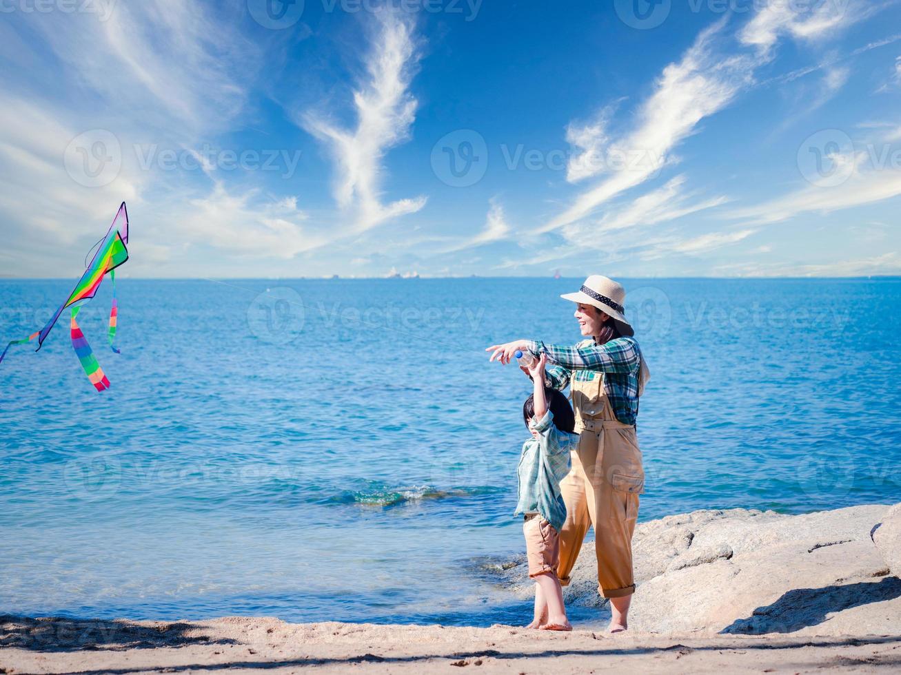 contento asiatico famiglia di madre e figlio lanciare un' aquilone in natura a il bellissimo cielo, madre e contento figlio nel il cielo durante un' soleggiato giorno su il spiaggia, solidarieta, estate, e vacanza concetto foto