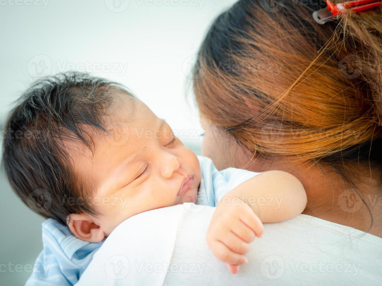 amorevole mamma trasporto sua addormentato neonato bambino su sua spalla a casa.ritratto di mamma Tenere addormentato infantile bambino su mani. madre abbracciare sua poco due mesi ragazza. foto