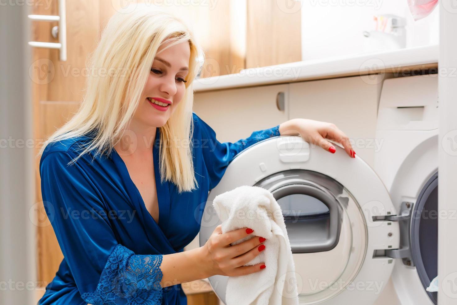 un' contento casalinga donna nel lavanderia camera con lavaggio macchina foto