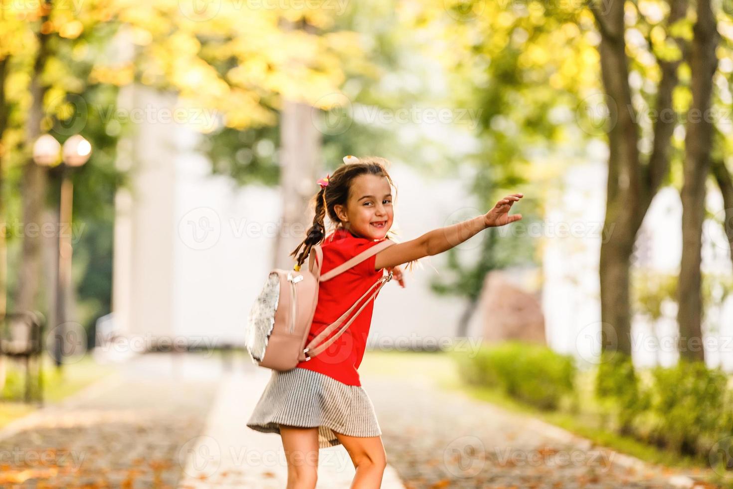 il poco scolara è in esecuzione con un' zaino e ridendo. il concetto di scuola, studia, formazione scolastica, amicizia, infanzia. foto