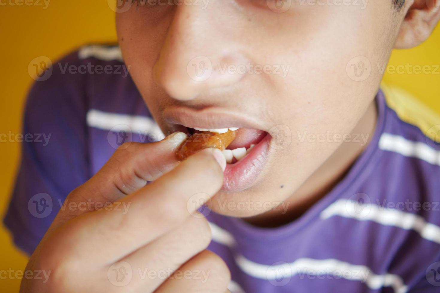 ragazzo mettendo cioccolato nel bocca foto