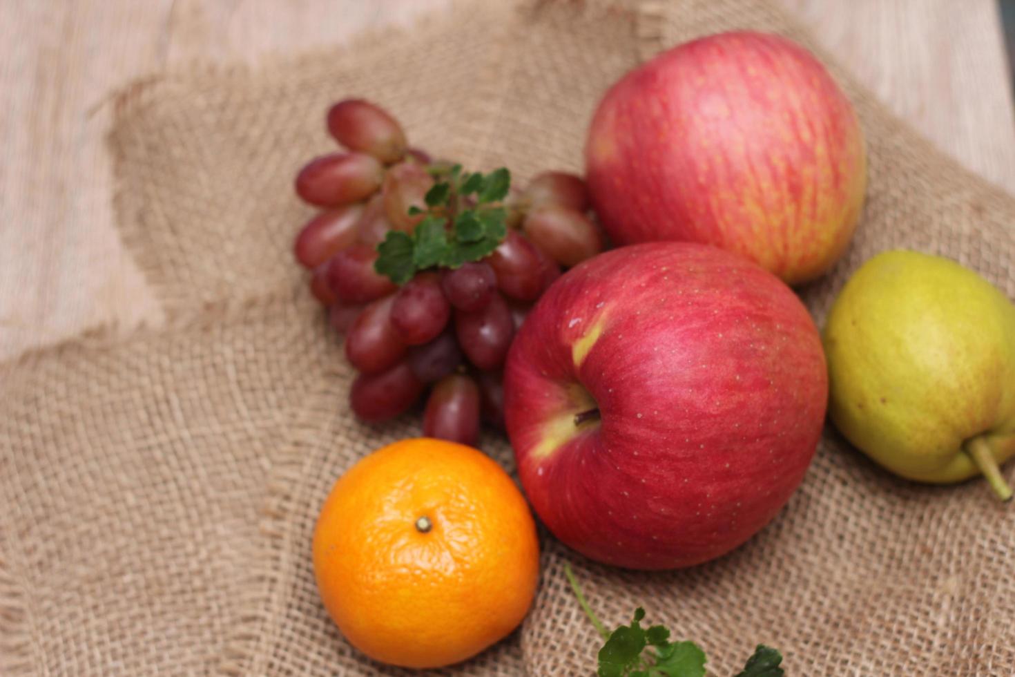 frutta con vitamina c quello siamo benefico per il corpo. posto su tela di sacco - arancia, uva, mela, guaiava foto