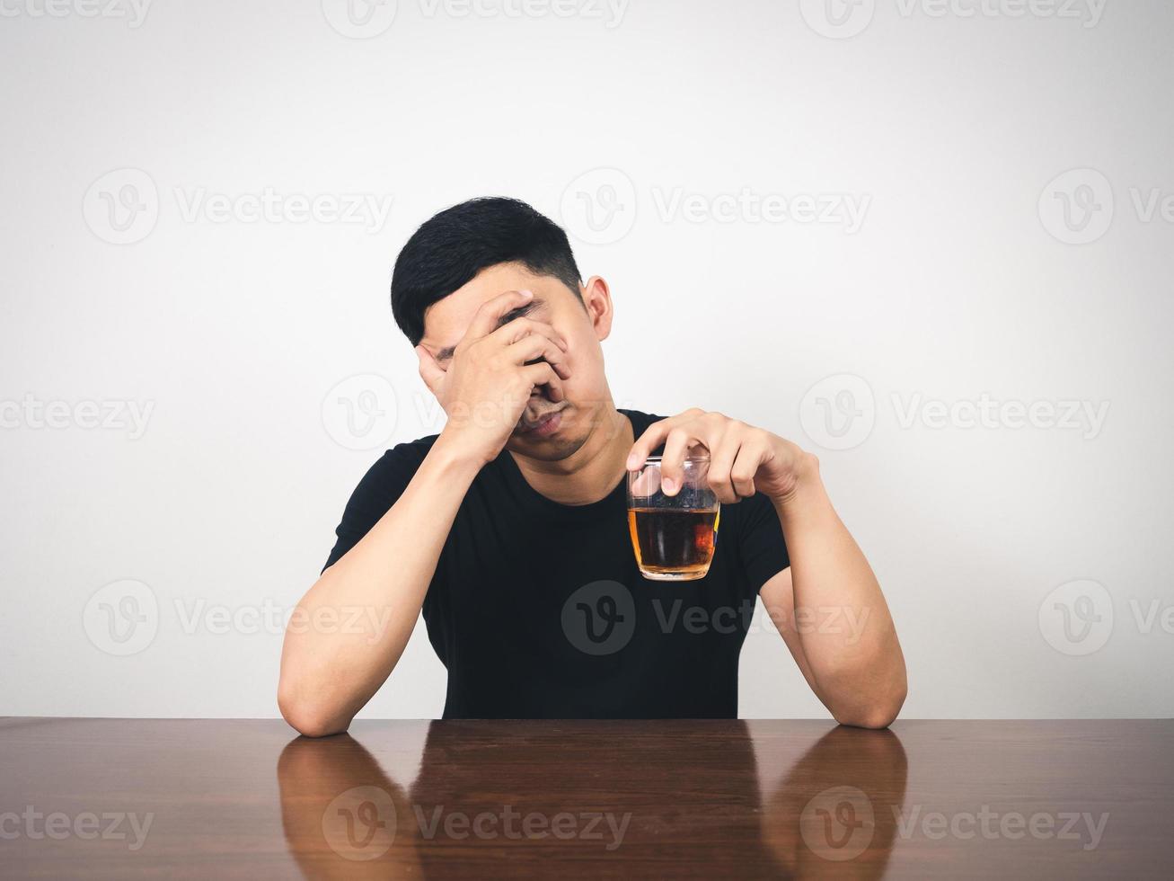 ubriaco uomo sedersi e hold bicchiere di alcool e vicino il suo viso foto