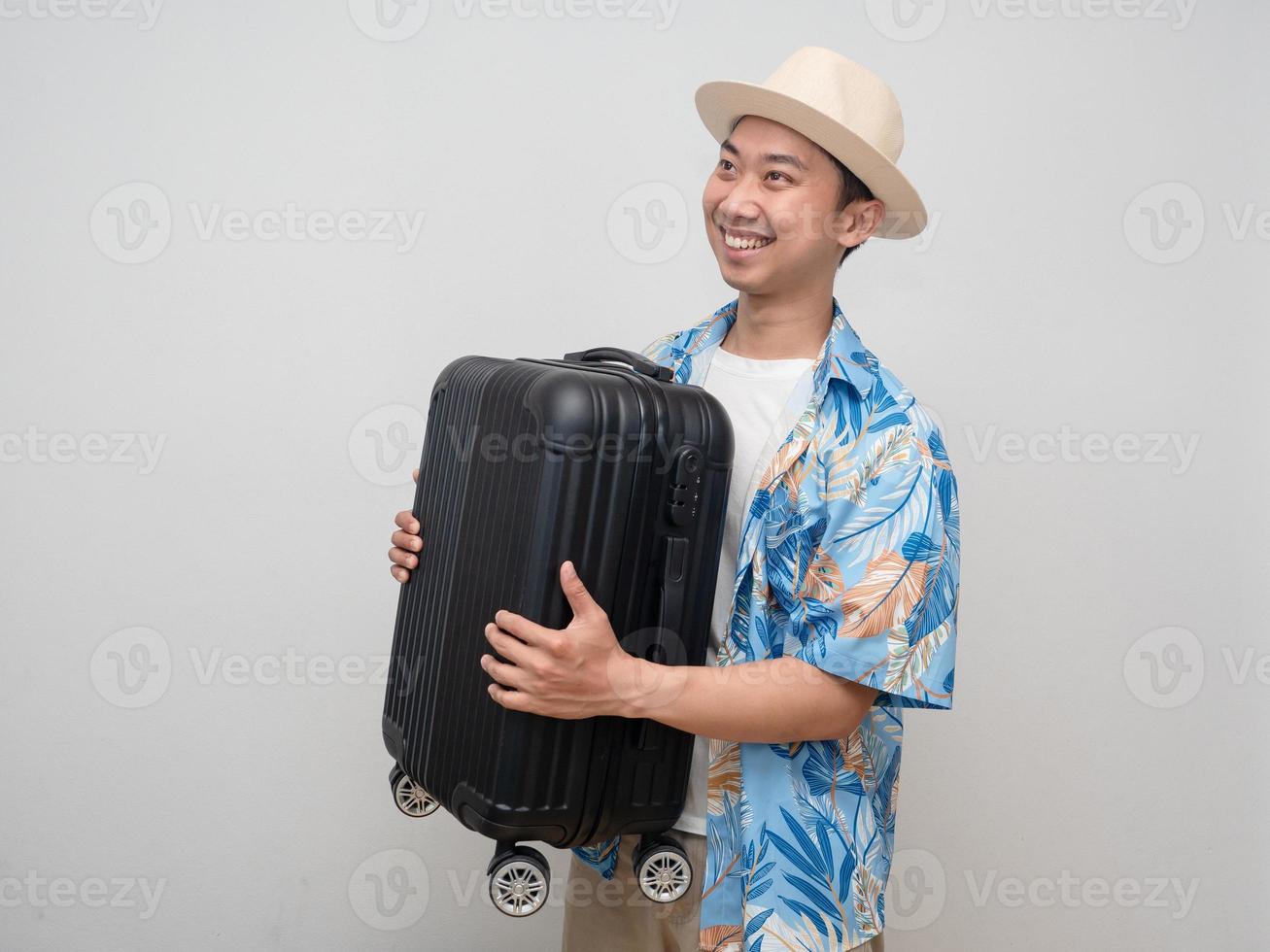 giovane viaggiatore uomo indossare cappello contento vacanza trasportare bagaglio foto
