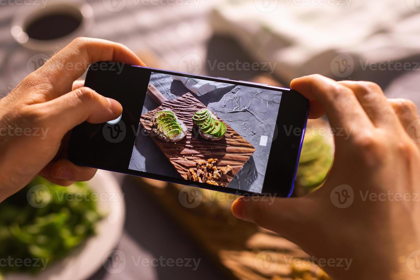 smartphone assunzione immagine a partire dal biologico salutare panini con avocado. uomo mano. foto