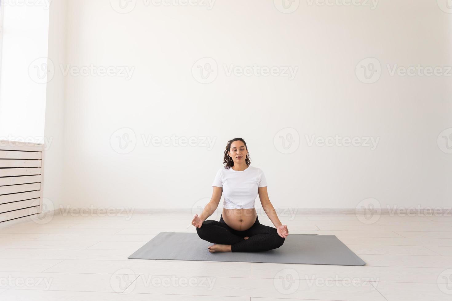 salutare bellissimo incinta donna medita prima yoga classe e rilassa mentre seduta su stuoia su il pavimento. concetto di fisico e mentale preparazione di corpo per parto. copyspace foto