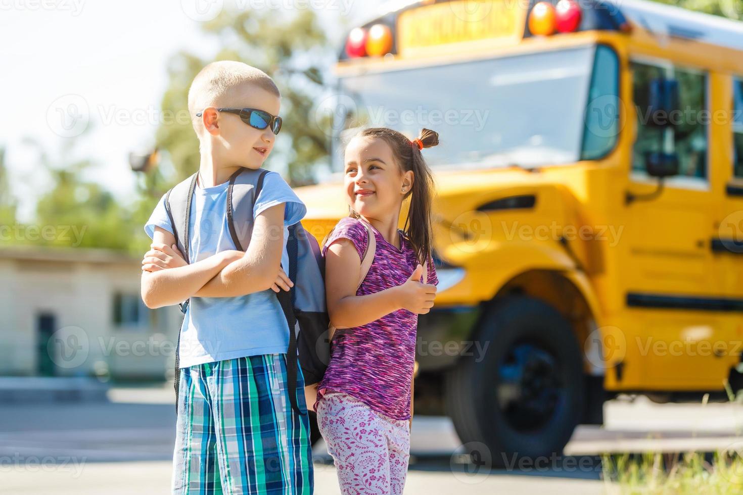 bellissimo poco scolara con compagne di classe vicino scuola autobus foto