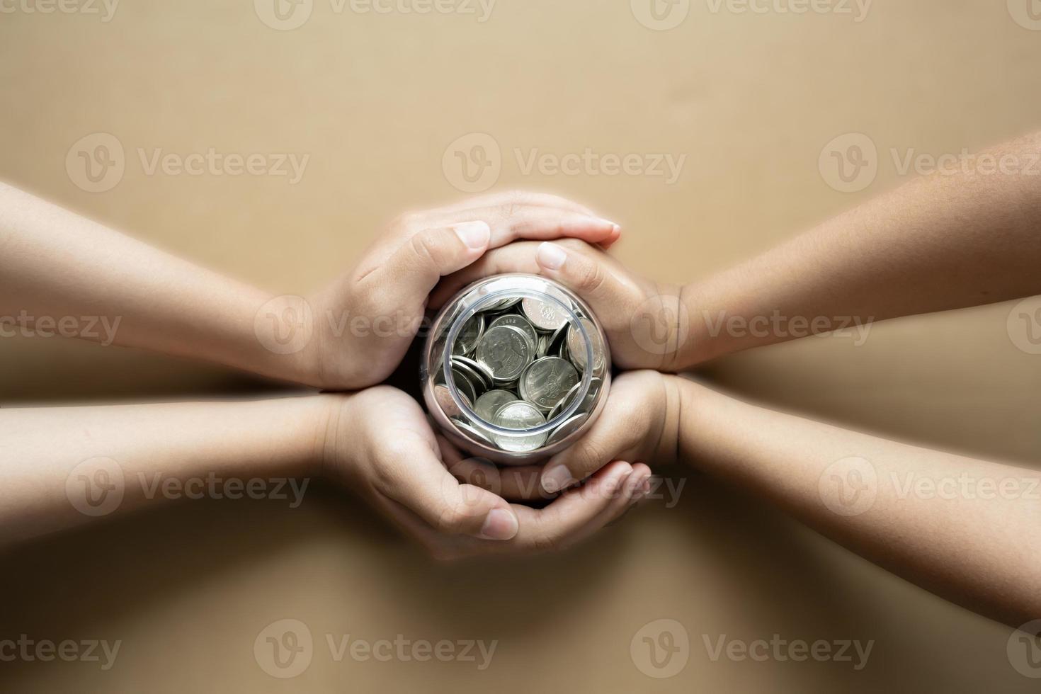 ragazzo mani Tenere monete nel un' vaso insieme come Salvataggio concetto per famiglia o formazione scolastica. foto