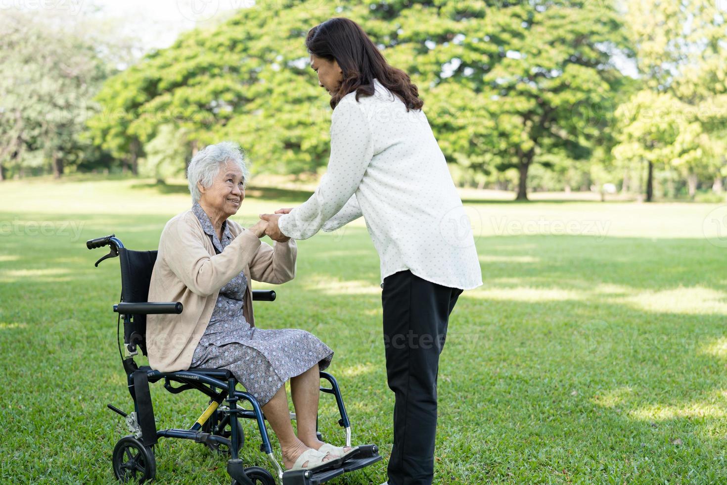 assistenza e cura del caregiver paziente asiatico anziano o anziano della donna che si siede sulla sedia a rotelle nel parco, concetto medico forte sano. foto