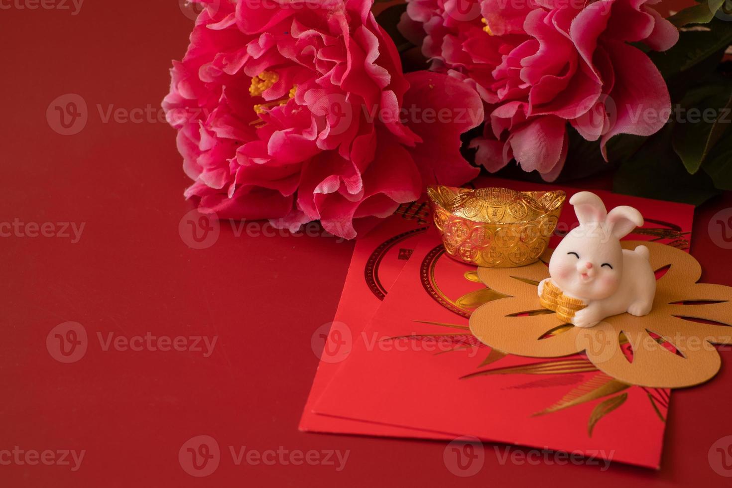 Cinese nuovo anno di il coniglio Festival concetto. mandarino arancia, rosso buste, coniglio e oro lingotto decorato con prugna fiorire su rosso sfondo. foto
