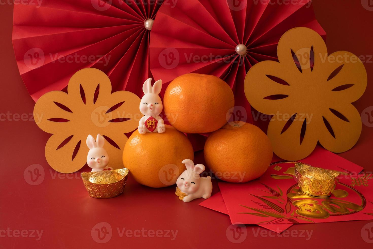 Cinese nuovo anno di il coniglio Festival concetto. mandarino arancia, rosso buste, coniglio e oro lingotto con rosso carta fan. tradizionale vacanza lunare nuovo anno. Cinese personaggio cai senso i soldi. foto