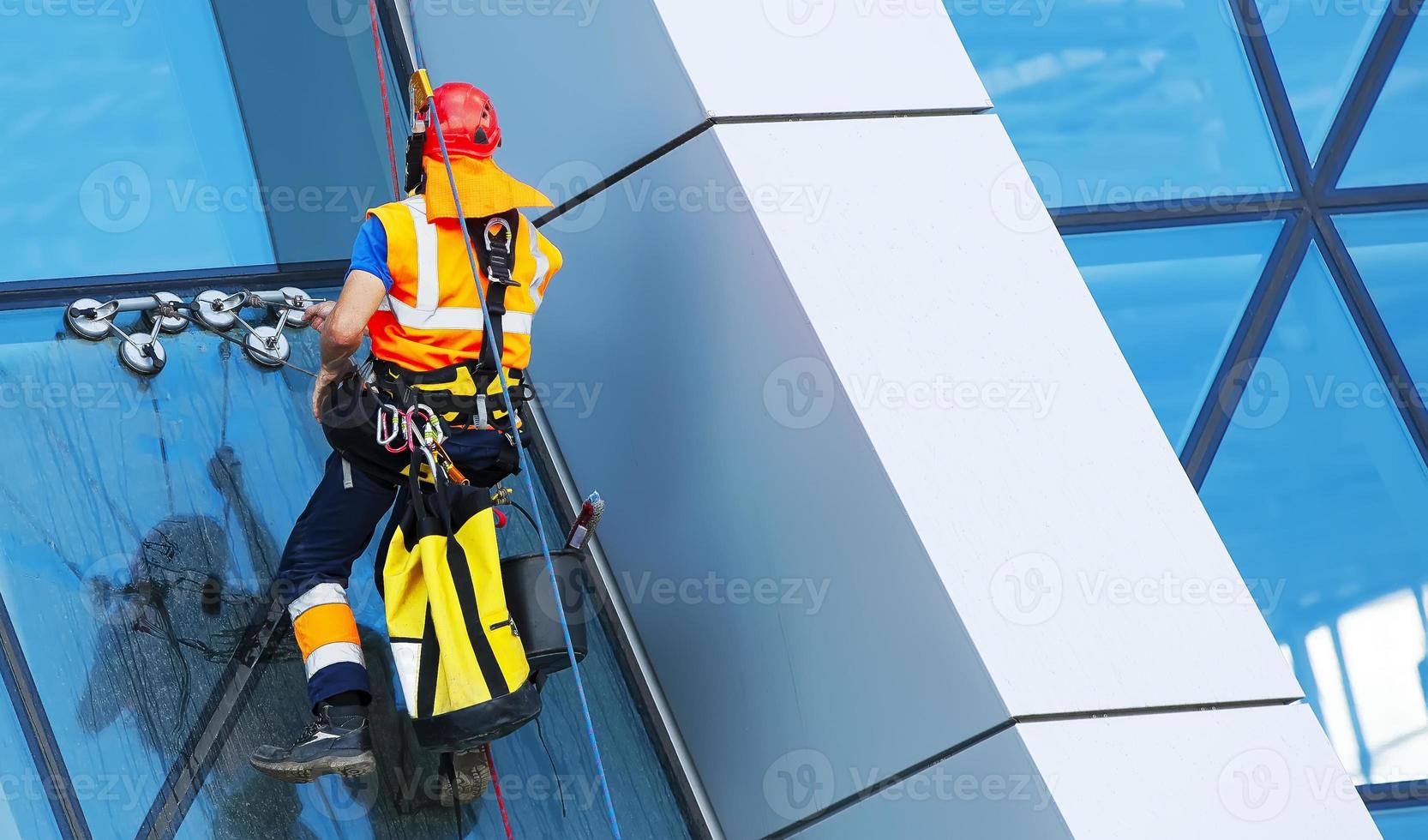 lavavetri lavorando su un moderno grattacielo di facciata in vetro foto