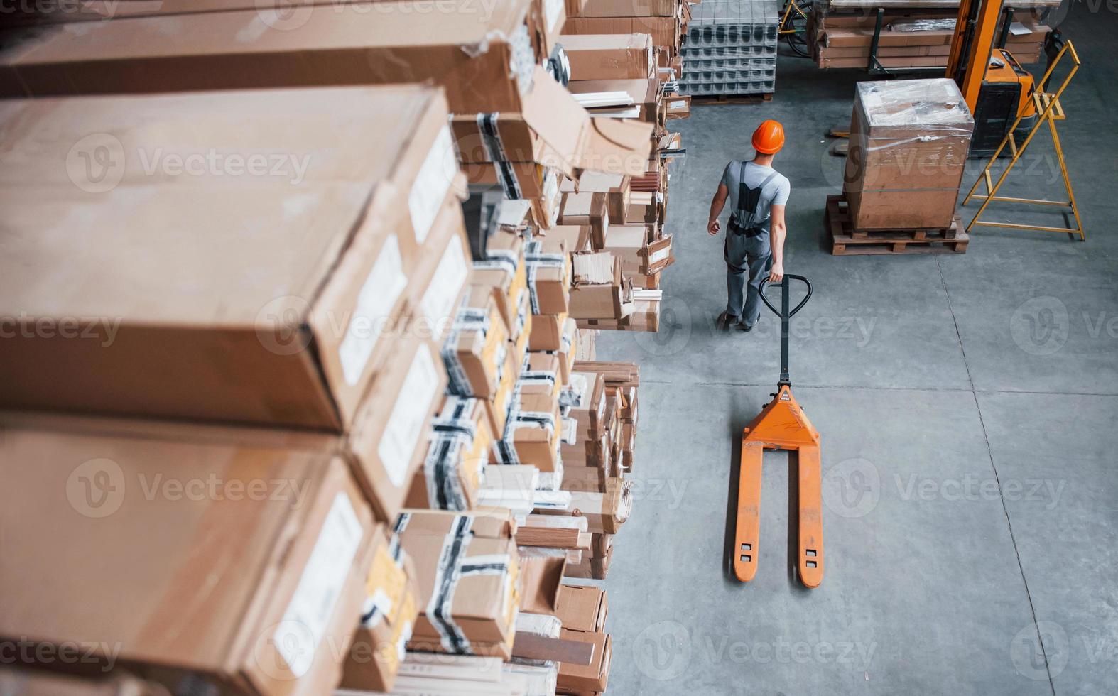 superiore Visualizza di maschio lavoratore nel magazzino con pallet camion foto