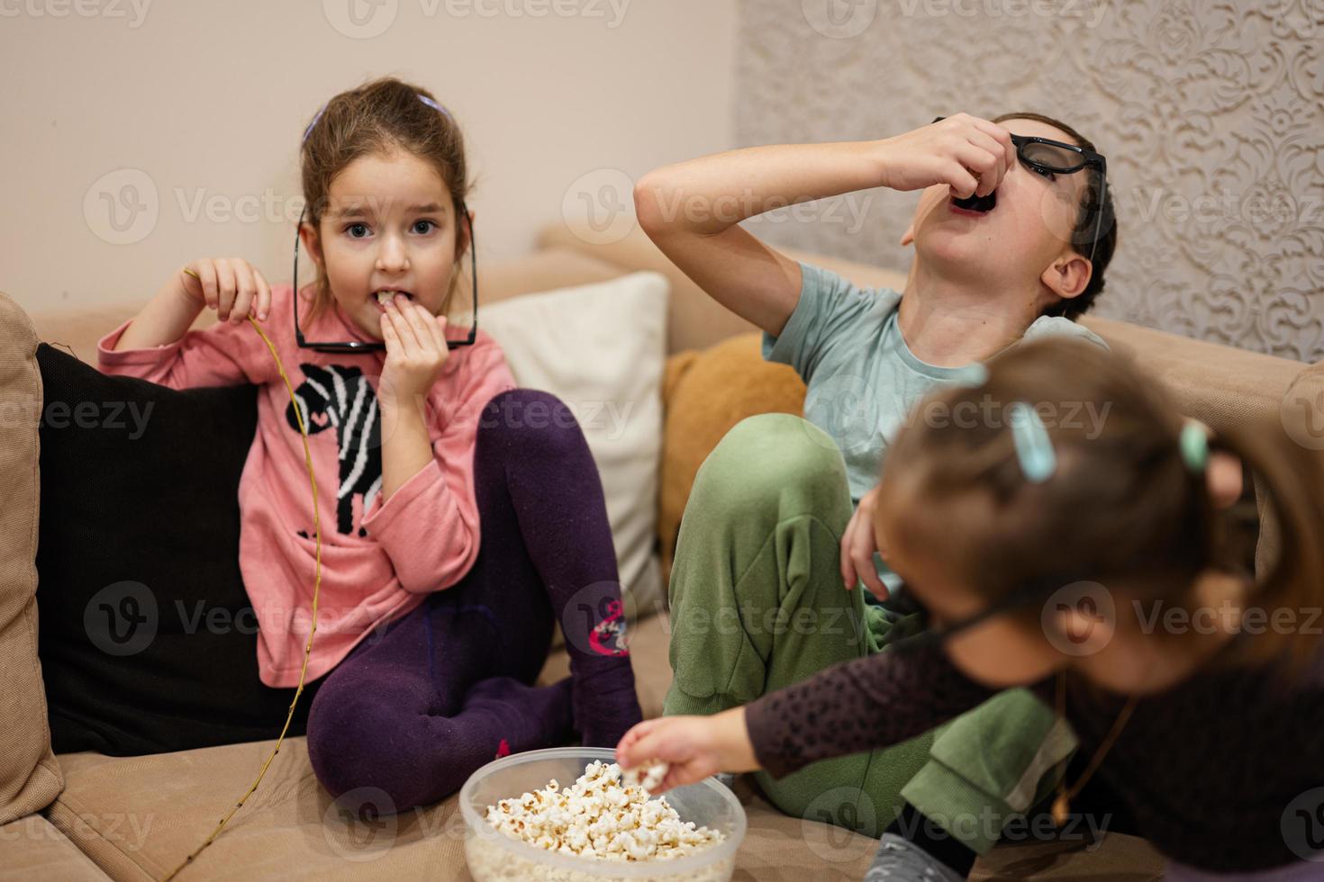 tre bambini seduta su il vivente camera, indossare 3d bicchieri Guardando film o cartone animato. foto